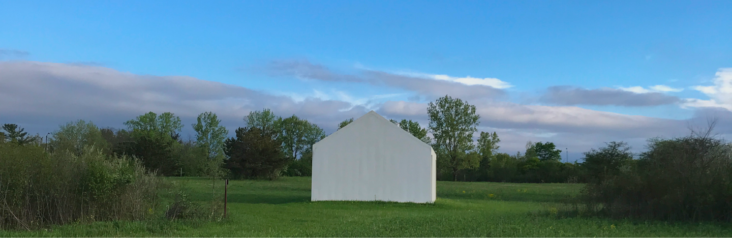 A large white concrete sculpture of a house in a prairie